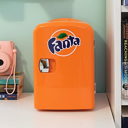 Orange Fanta mini fridge on a shelf with books.